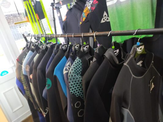 A rack of used wetsuits supplied for film use, keeping it real so they do not look brand new.